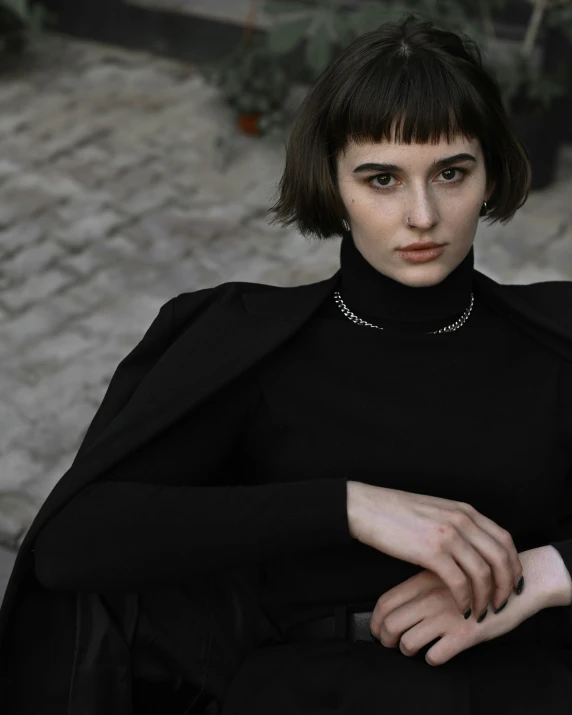 a woman sitting down in a black dress with her arms crossed