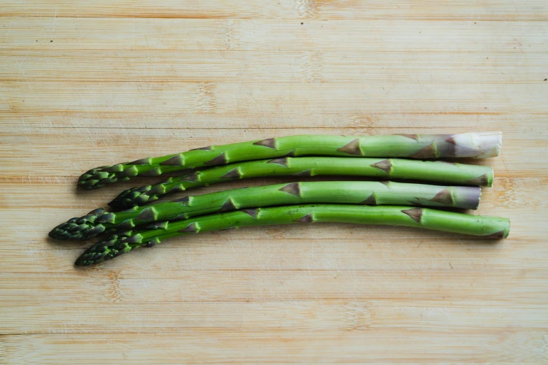 four asparagus are on a wooden  board