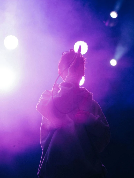 a man is holding a microphone on stage at night