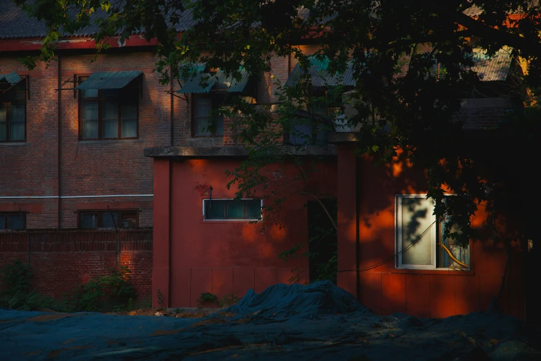 an old red building stands in the shadow of leaves