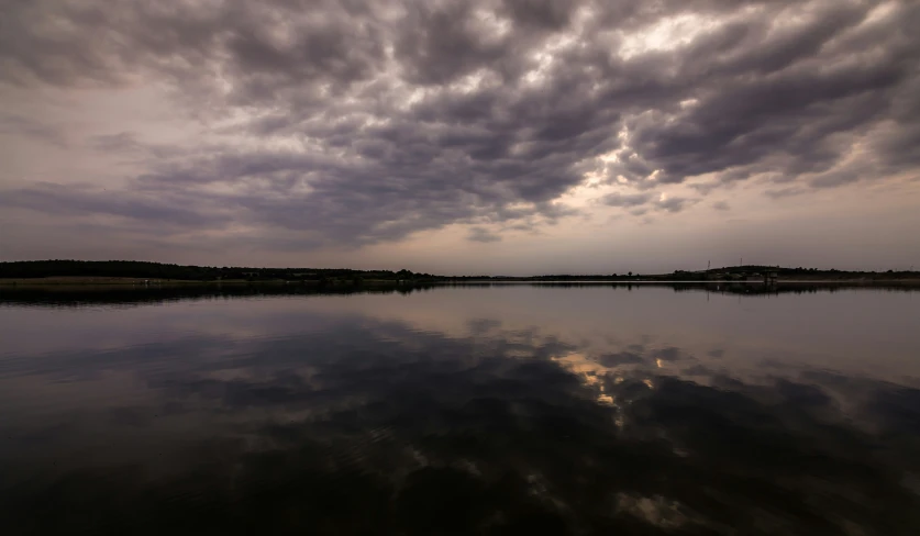 the clouds are reflected in a calm body of water