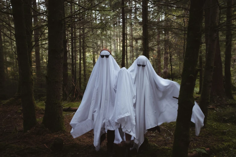 two ghostly people stand next to each other in the woods