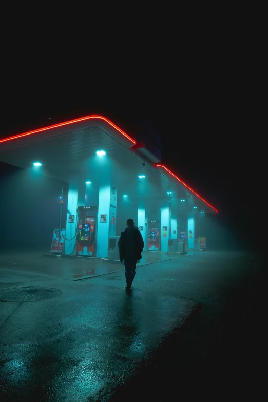 a man walks toward the gas station at night