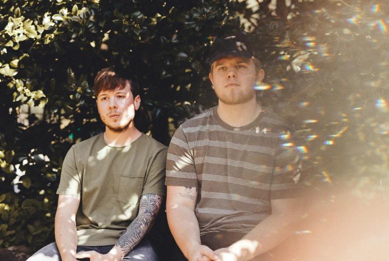 two men sitting in front of a tree while they are making their way to soing