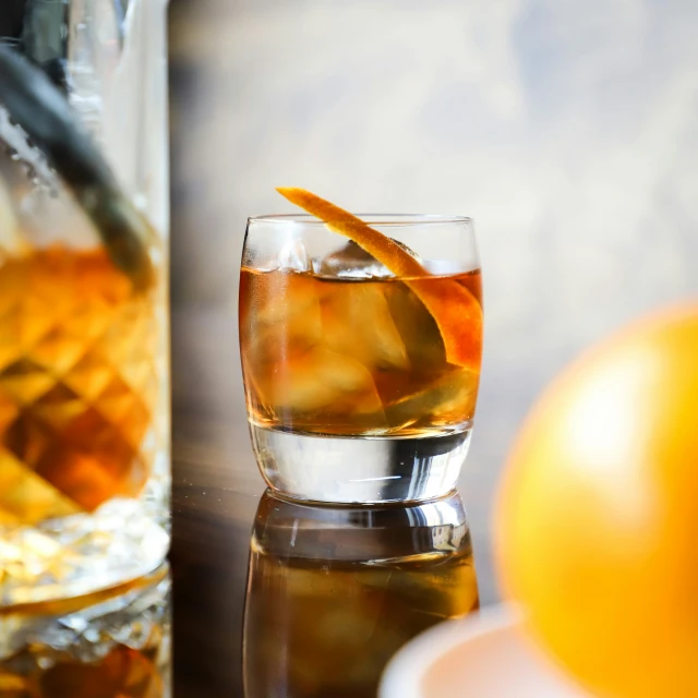 a glass of liquor next to an orange