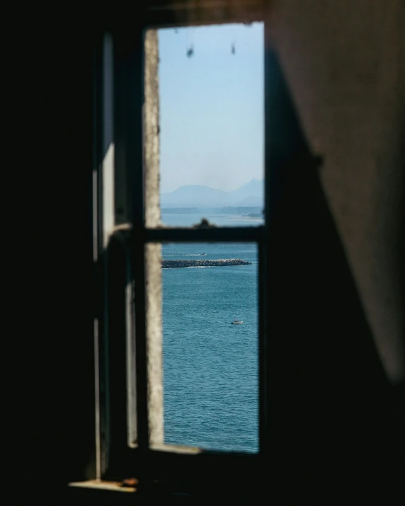 a view of a distant sailboat out of an old window