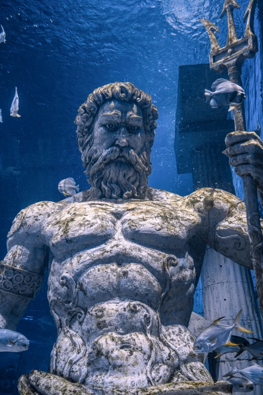 a statue of god or a man standing under water with a spear in hand