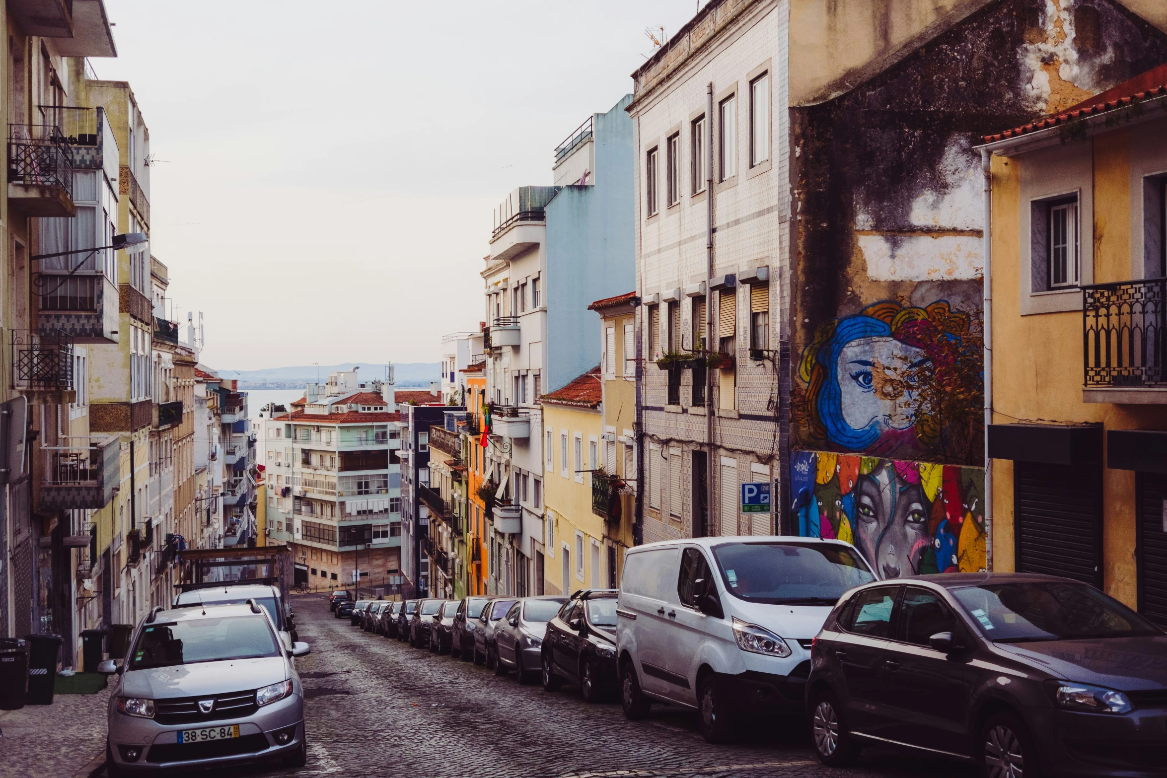 several cars parked on a narrow street near buildings