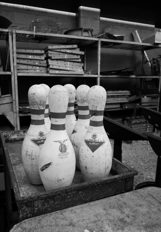 four bowling pins, sitting in front of a bookshelf