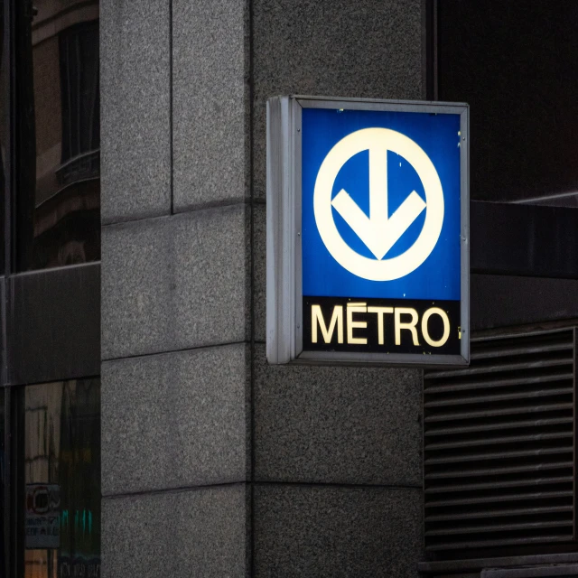 a metro sign hanging from a building next to it's door
