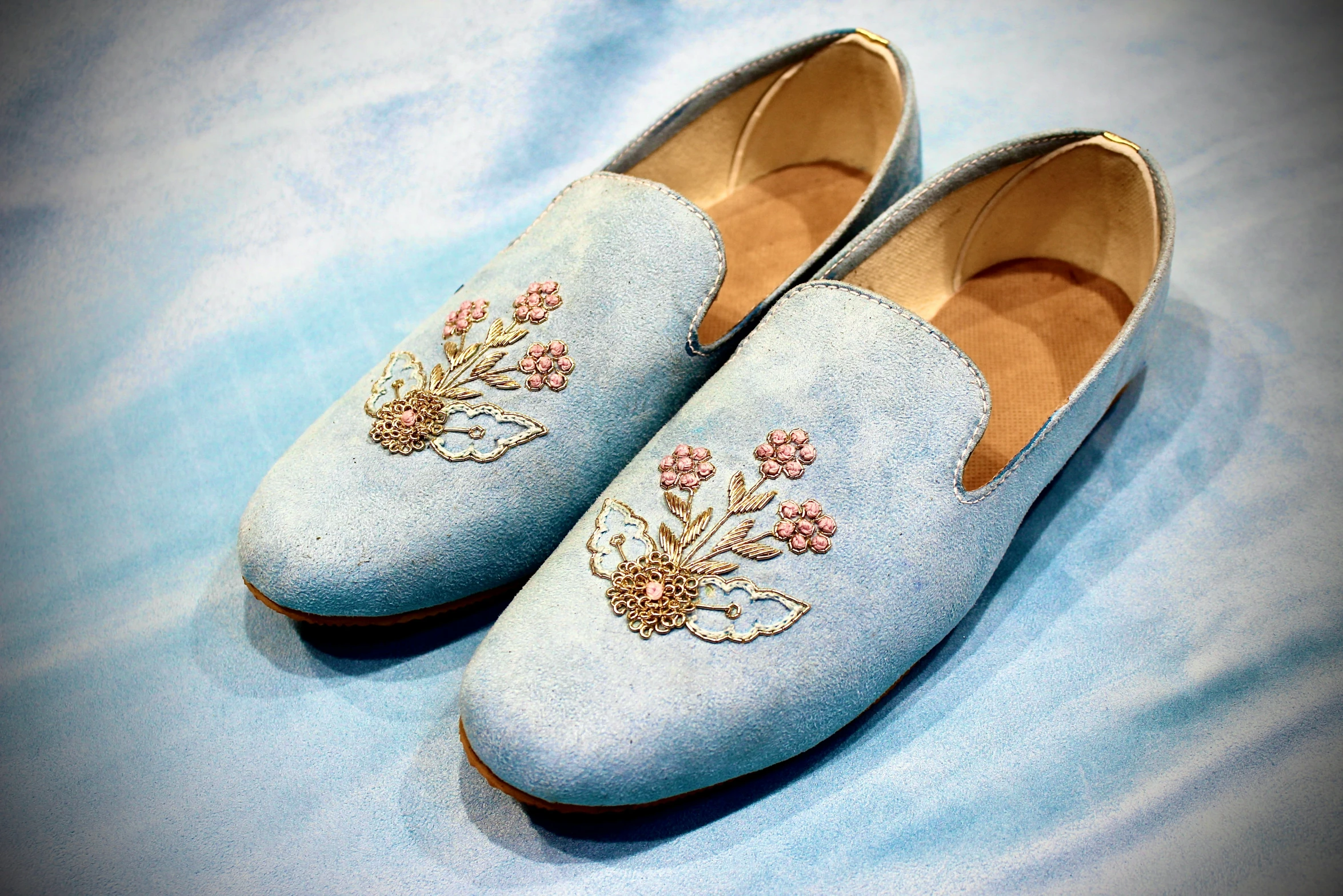 blue slippers with pink flowers and gold thread on the bottom