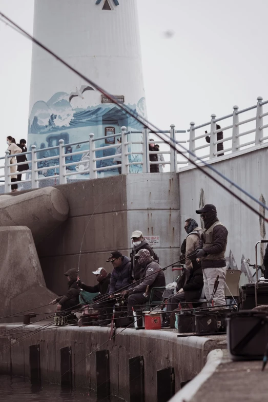 several people sitting on the dock next to a lighthouse