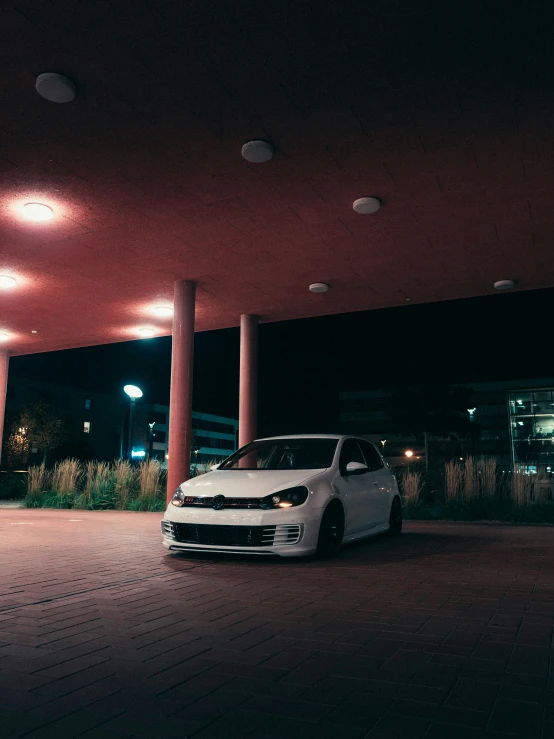 a white car is parked under an overhang at night
