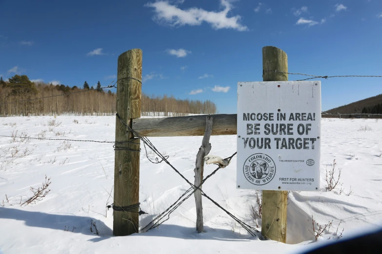 a wooden fence with barbed wire and sign in front of it