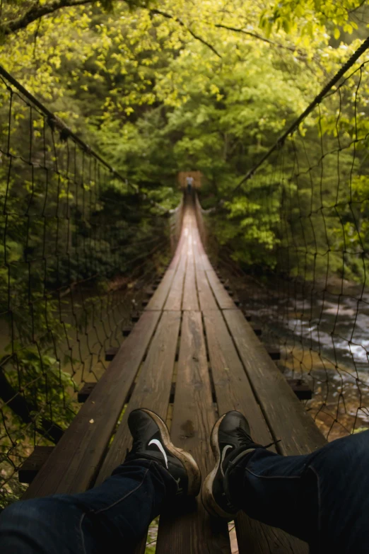 view of two people's feet from a foot bridge