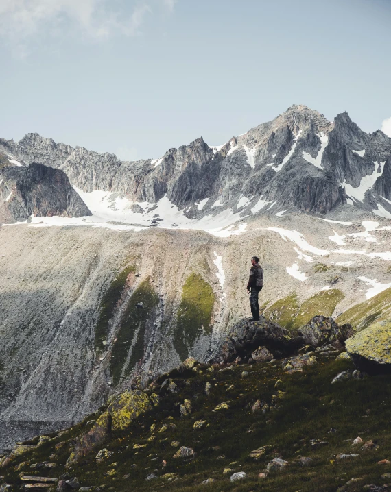 man standing on a hill, overlooking the mountain range