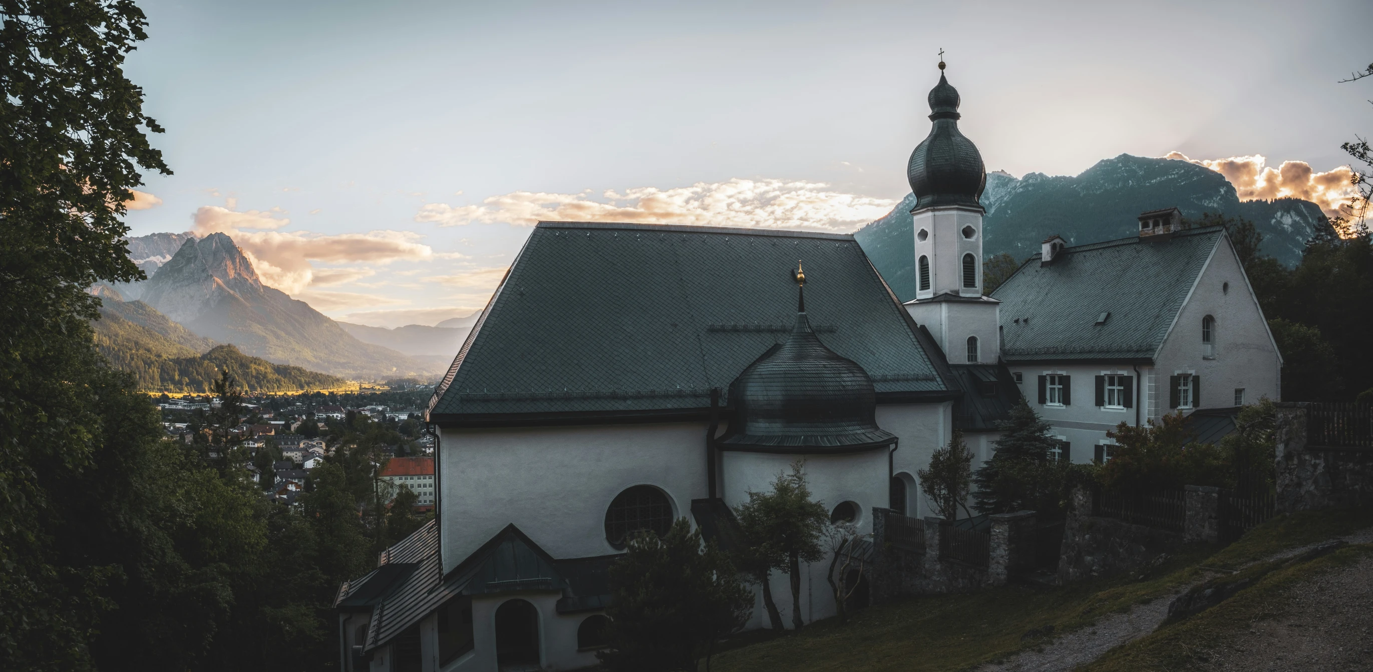 a church on the hill with mountains in the background