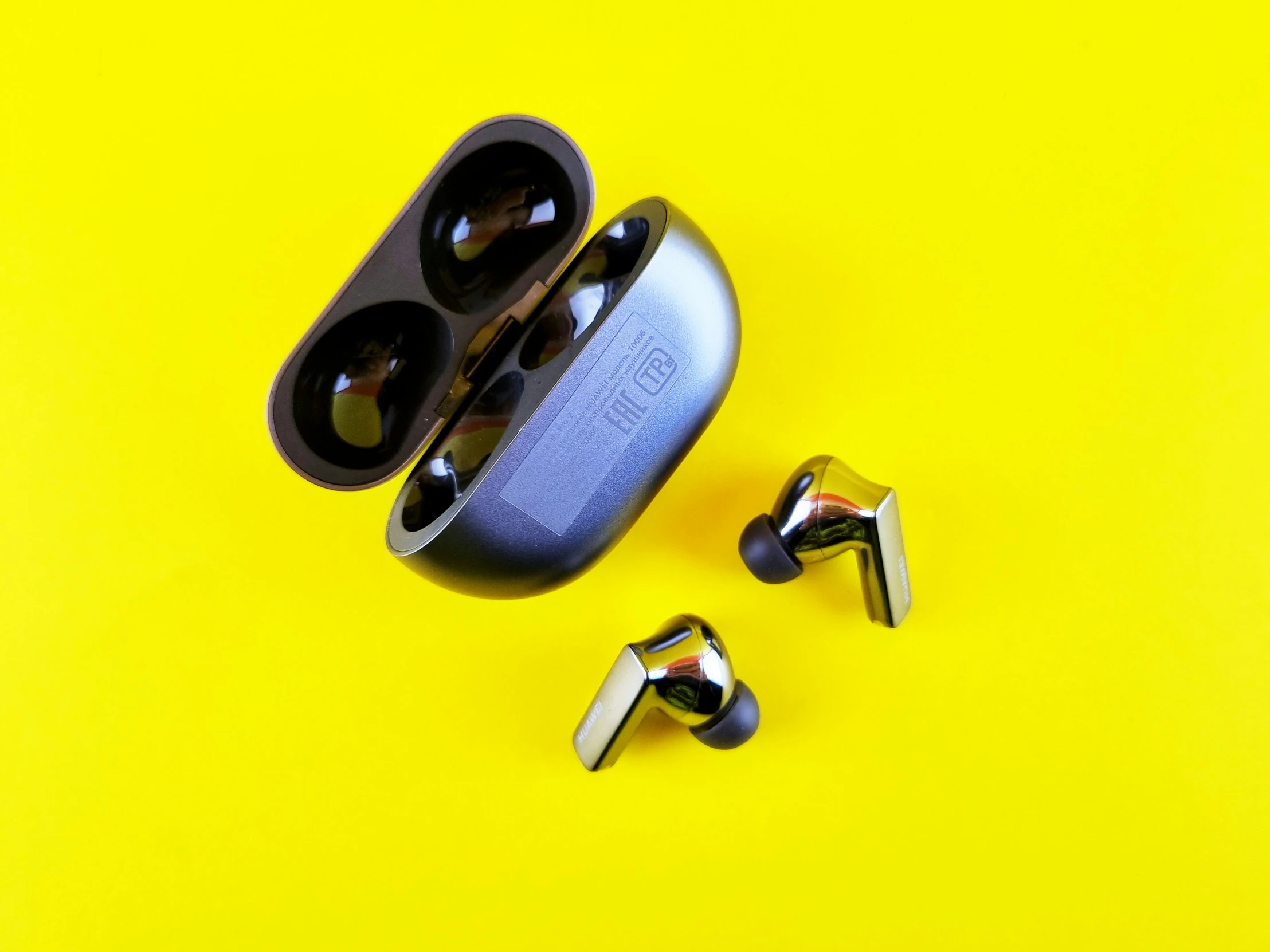 a pair of metal ear buds and screws on a yellow surface