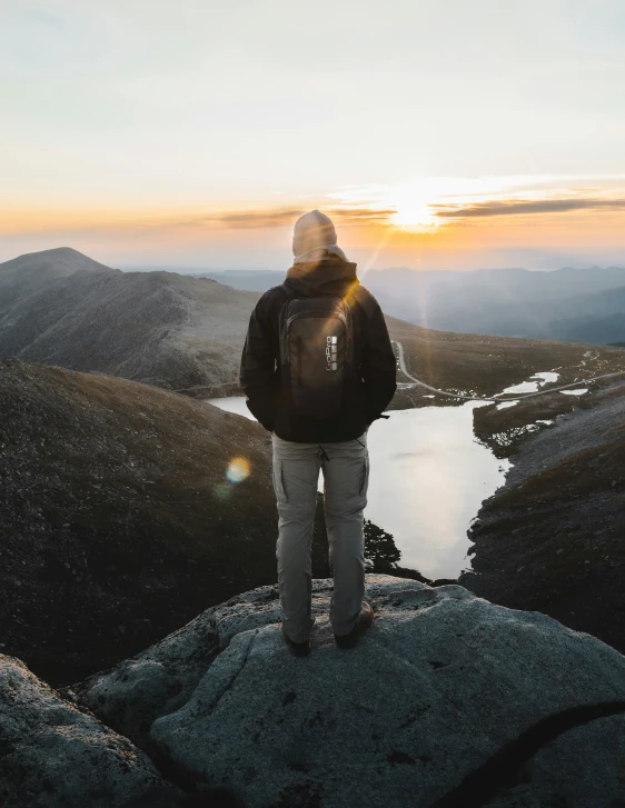 the person on top of a rock looks out at a river