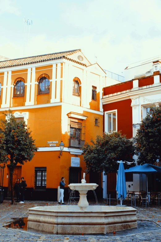 a fountain in front of an orange building