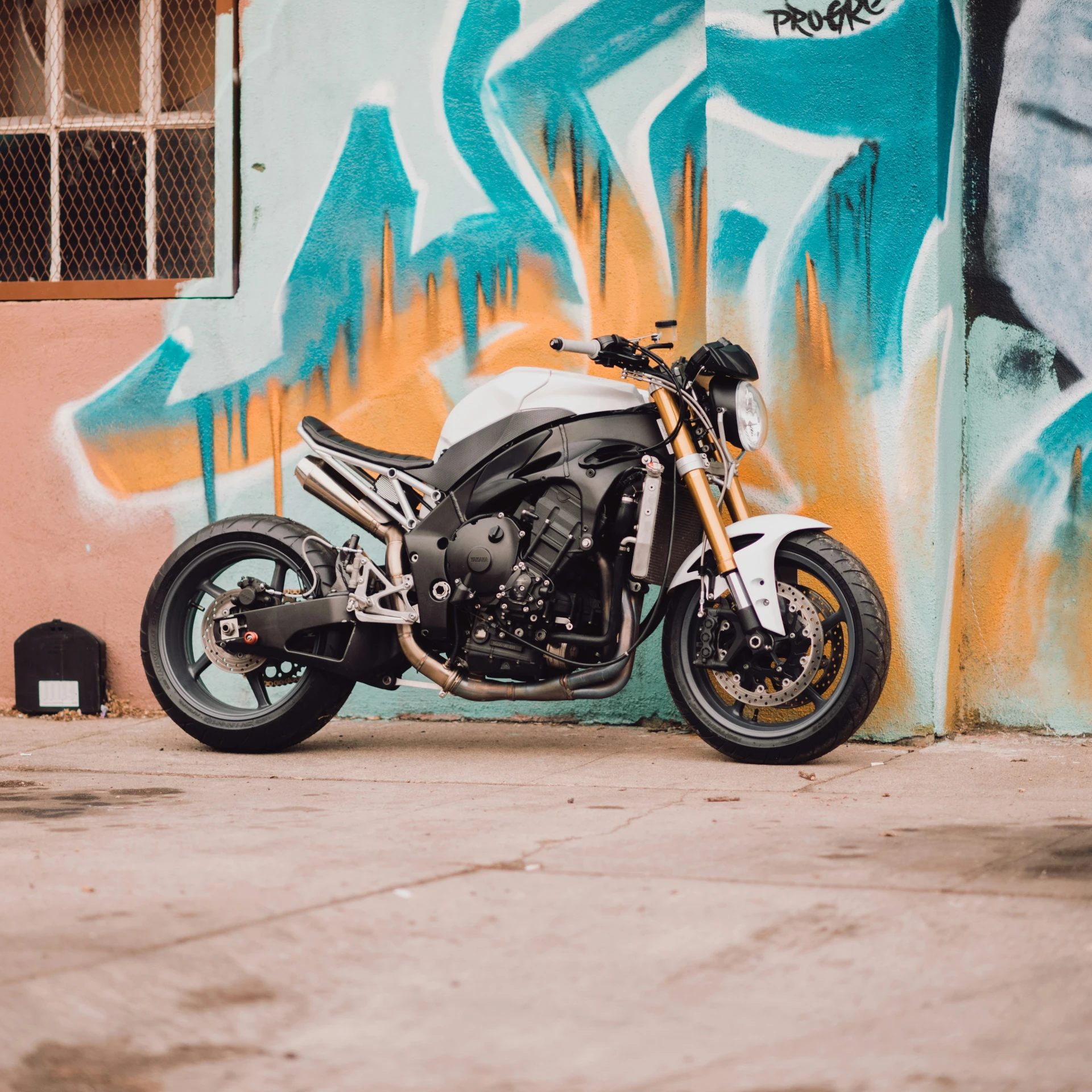 a parked motorcycle next to graffiti on a wall