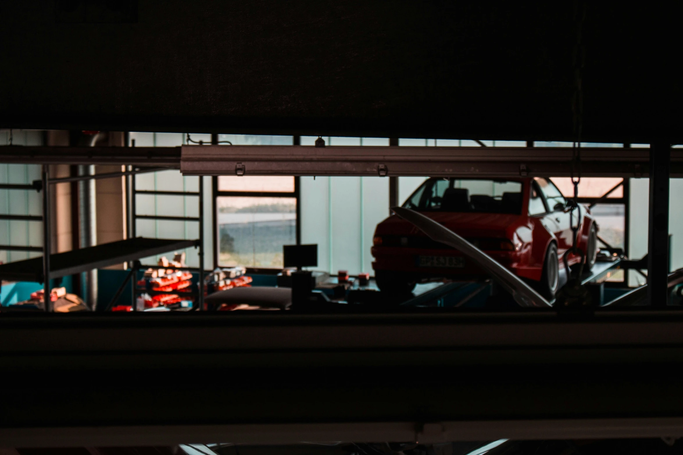 a red car sitting in a garage near other vehicles