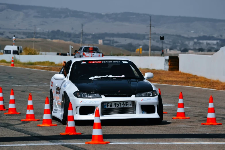 a car driving down the road between orange traffic cones