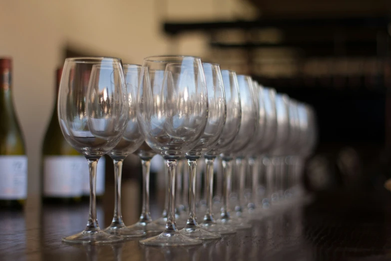 a row of empty wine glasses sitting next to bottles of wine