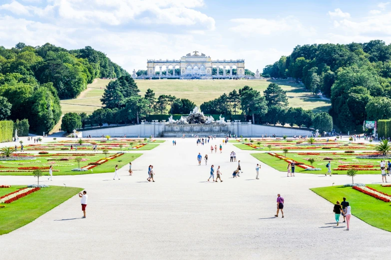 people walking in the foreground near an area with a lawn and flowers