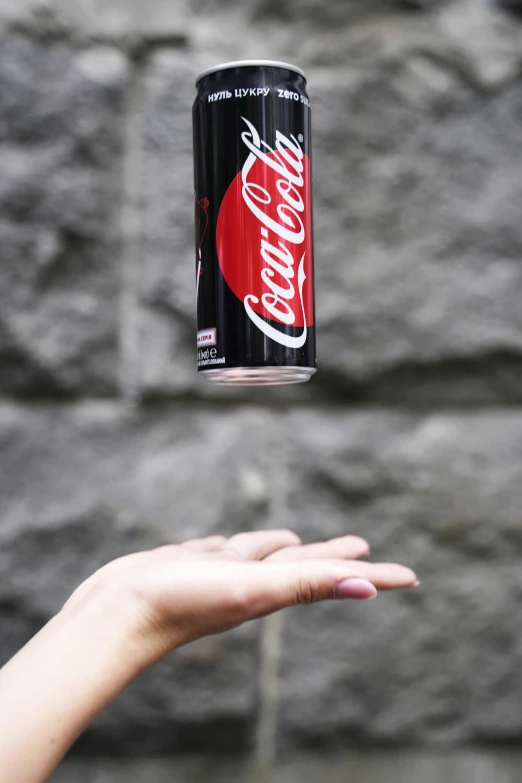 there is a hand holding a can of coca cola