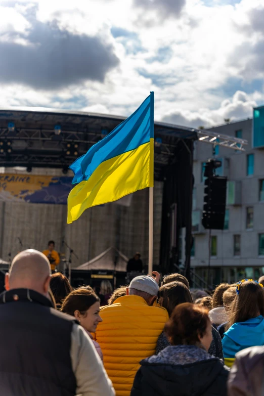 a yellow and blue flag on a pole in the middle of people