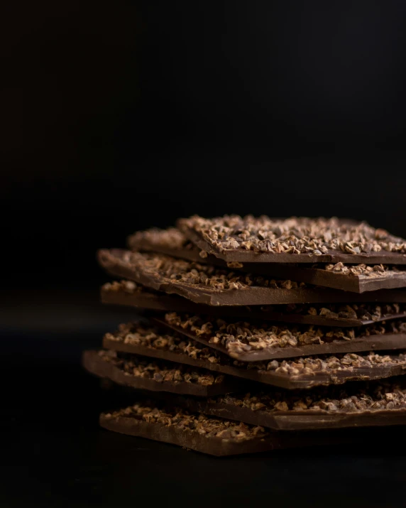 a stack of chocolate pieces are in front of a black background