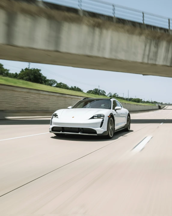 white porsche sports car driving down the highway