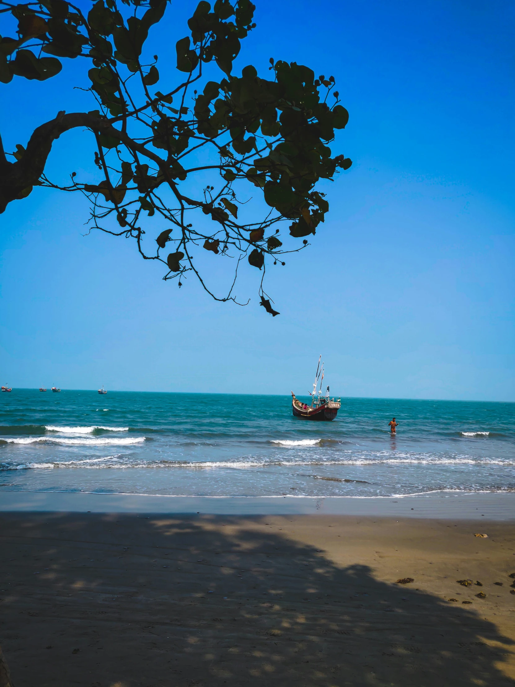 the ocean shore with a small boat in the distance