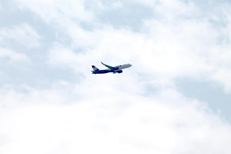 an airplane flies by a cloudy blue sky