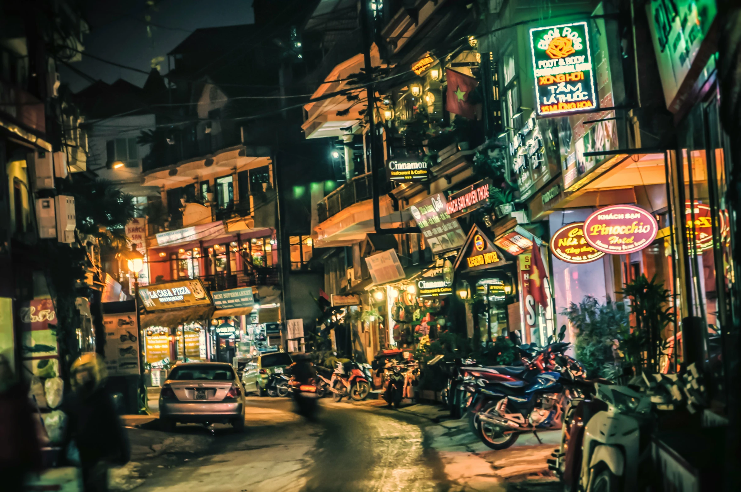 traffic driving down a street with neon lights on the buildings