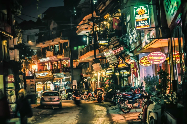 traffic driving down a street with neon lights on the buildings