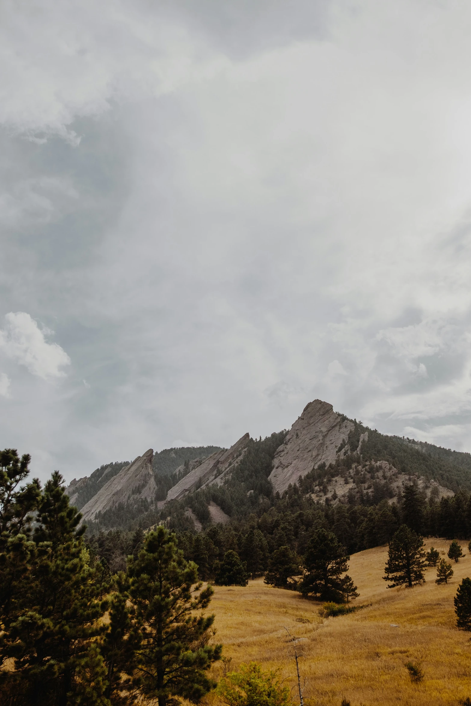 a tall hill with a very tall mountain in the distance