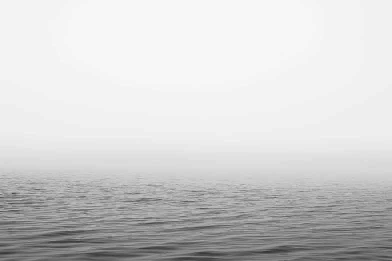 an ocean in the fog covered sky with a light house