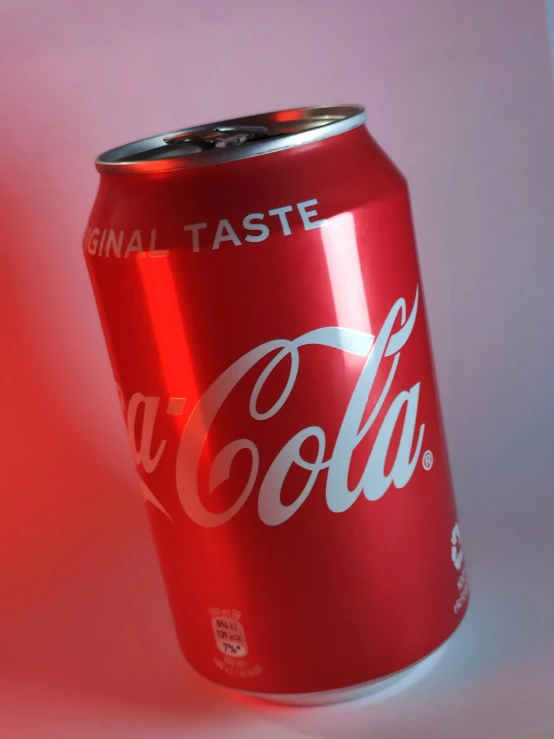 a can of cola on a red surface