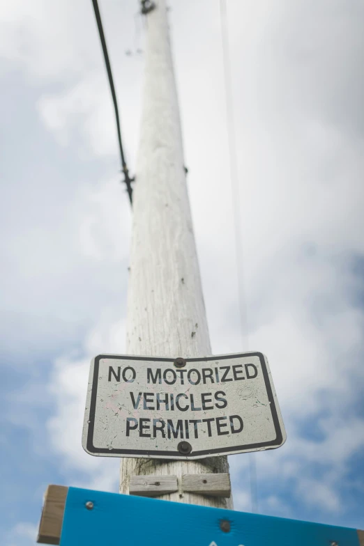 a sign posted on a wooden post says no motorized vehicles permitted