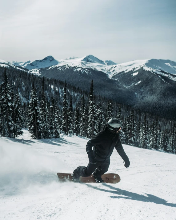 snow boarder riding down a slope near the forest