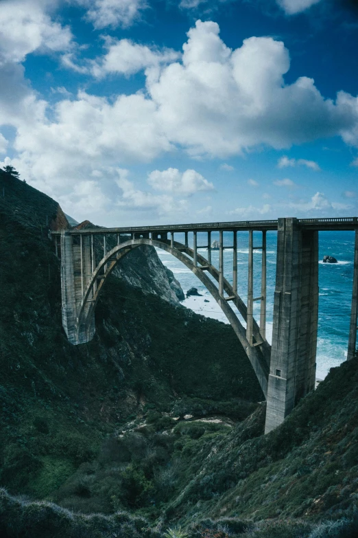 a bridge over the water with the mountains in the background