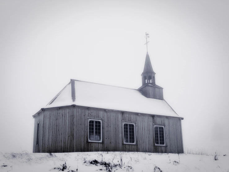 a black and white image of a snowy church with a steeple