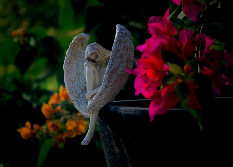 a bird sitting on top of a black pot filled with flowers