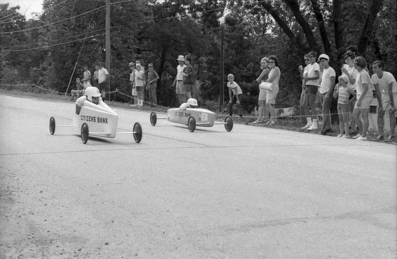 an old po of two racing cars being watched by people