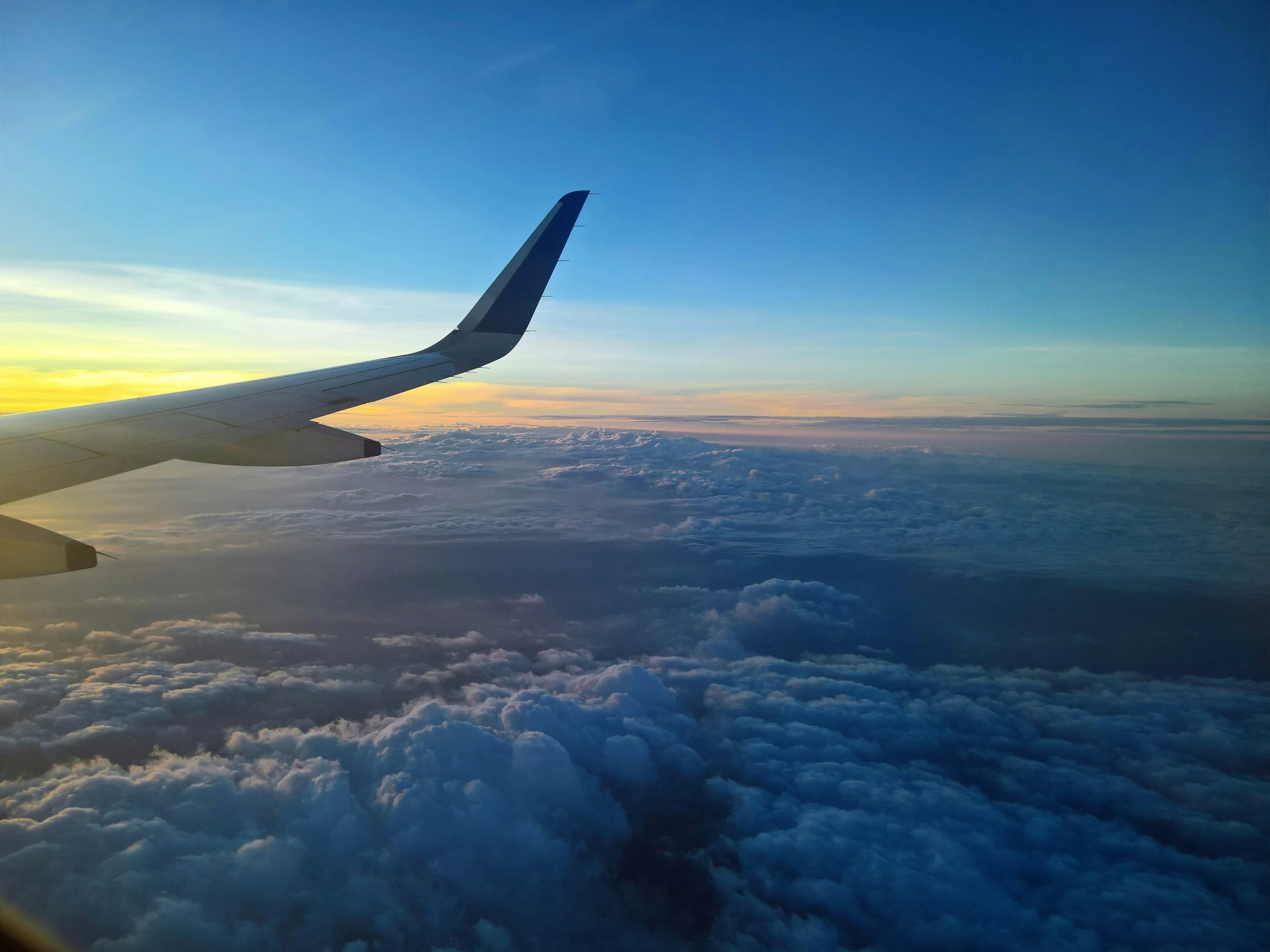 an airplane wing high above the clouds during sunset