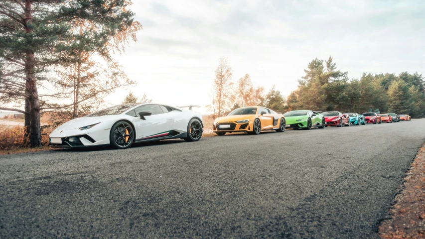 a line of lamborgs on a road at sunset