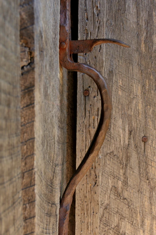 an old rusty metal hook on a wooden door