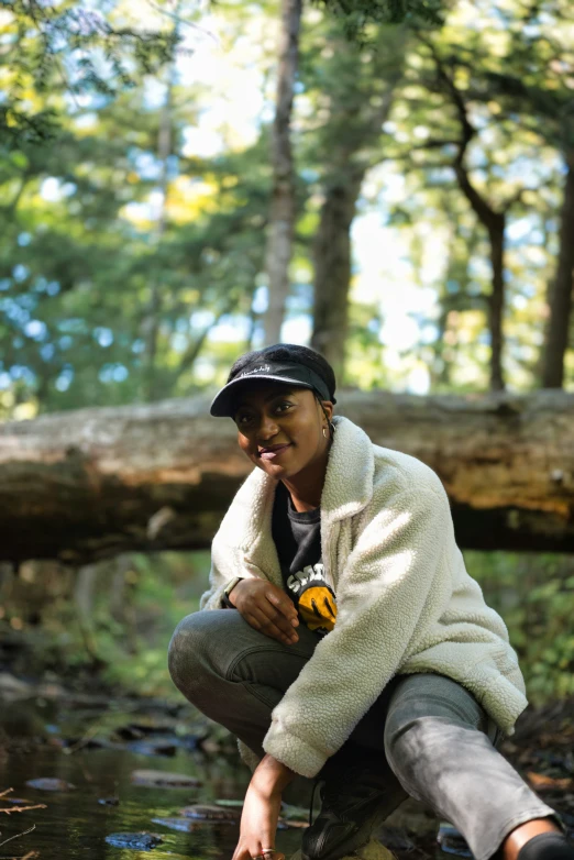 a person crouching down in a stream in the forest